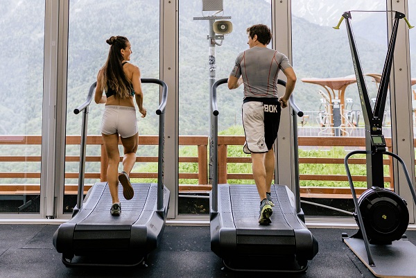 Een zicht op een vrouw en man die hardlopen op een loopband