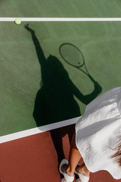 Een blik op een schaduw bij opslag van een tennisspeelster