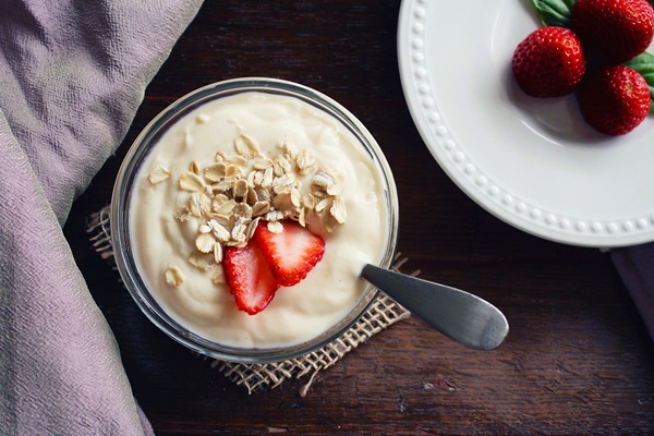 Een foto van een pot yoght met muesli en aardbei