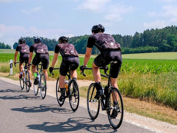 Een blik op een groep van 4 renners die achter elkaar fietsen.